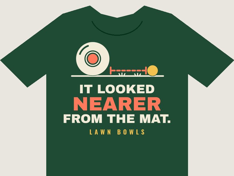 Bottle-green T-shirt preview with a cream lawn bowl stopped well short of a yellow jack, a coral dashed measure between them, above the words IT LOOKED NEARER FROM THE MAT. in cream and coral, and LAWN BOWLS in small yellow letters.