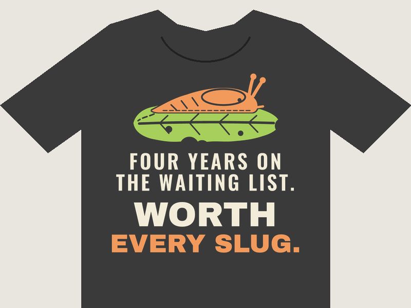 Charcoal T-shirt preview with an orange slug on a nibbled green lettuce leaf above the words FOUR YEARS ON THE WAITING LIST. WORTH EVERY SLUG. in cream and orange.